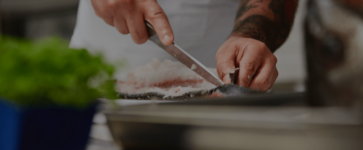Up-close photo of sushi chef filleting fish.
